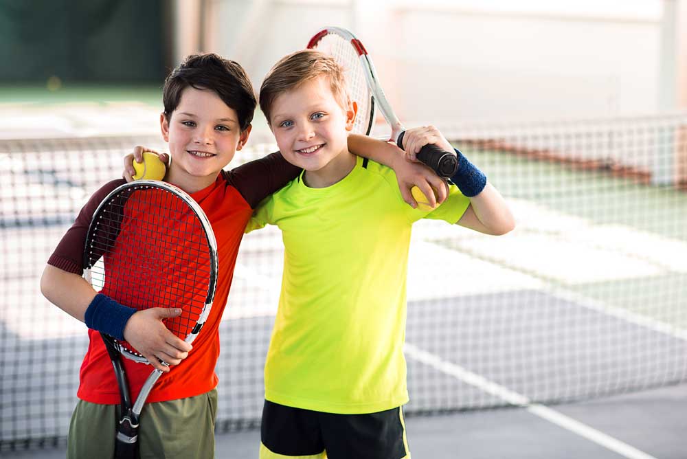 zwei Jungen mit Tennisschlägern in der Hand
