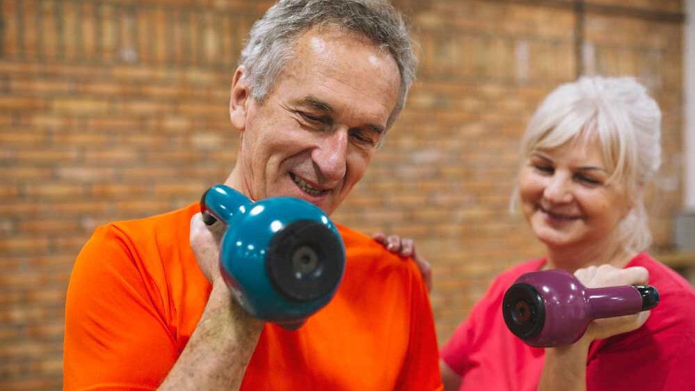 Aktiv ins neue Jahr - Zwei gut gelaunte ältere Menschen trainieren gemeinsam mit Hanteln – ein motivierendes Bild für die ‚Bring-a-Friend‘-Aktion unseres Fitnessstudios in Pirna.