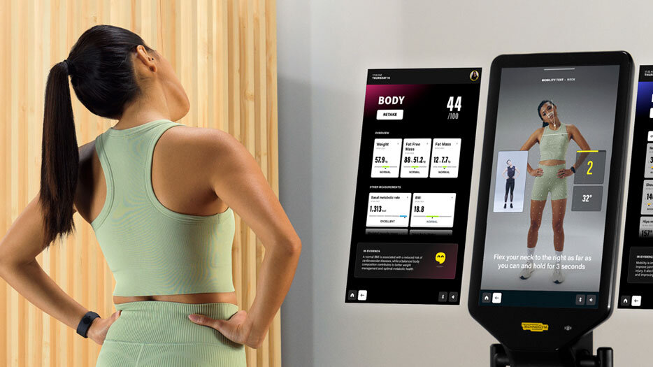 Eine Frau steht seitlich vor einem 4D-Körperscanner. Vor ihr sind mehrere schmale, vertikale Displays angeordnet, die unterschiedliche Analyseoberflächen zeigen, darunter Körpermaße, ein 3D/4D-Avatar und Haltungsdaten.