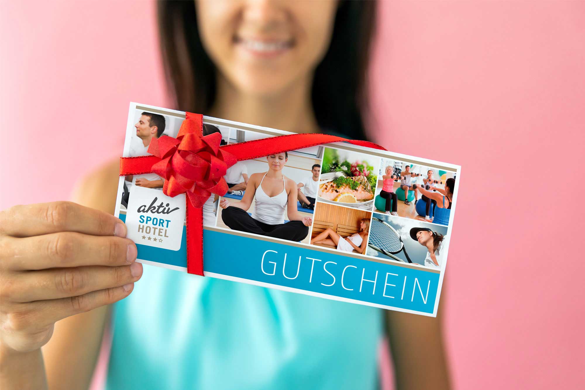 Symbolbild für die perfekte Geschenkidee: Eine lächelnde Frau präsentiert einen Hotel-Gutschein, der liebevoll mit einer großen, roten Schleife verziert ist. Auf der Gutscheinkarte ist eine Collage aus verschiedenen Urlaubsmotiven (Wellness, Aktivität, Genuss) zu erkennen. Der fröhliche, rosafarbene Hintergrund unterstreicht die Freude am Schenken.