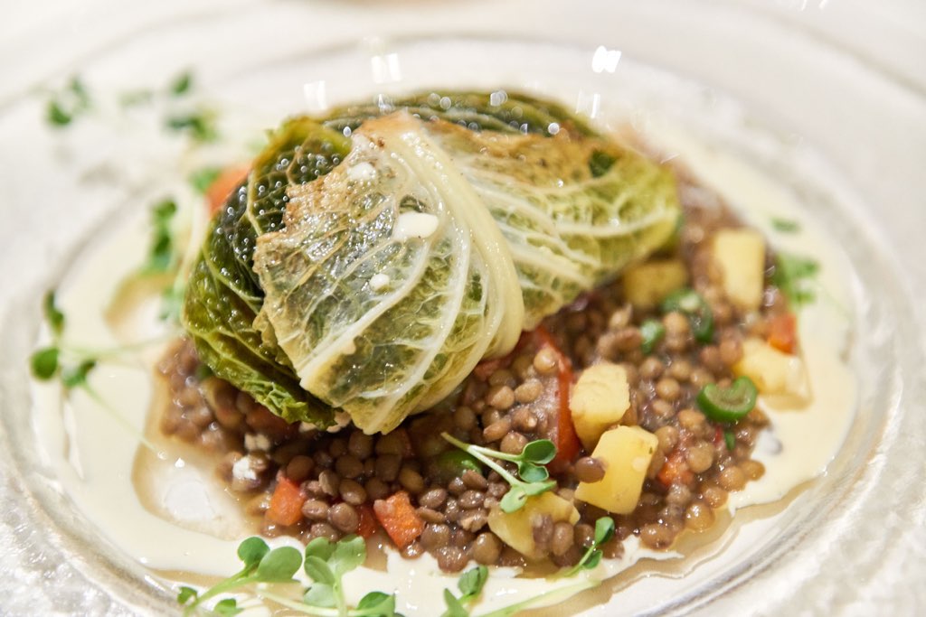 Das Foto bringt eine frisch zubereitete, saftige Kohlroulade auf einem Bett aus Linsen und bunt gemischtem Gemüse ins Rampenlicht – die aromatischen und regionalen Zutaten machen sofort Appetit und repräsentieren die saisonale Vielfalt der kreativen Küche im Restaurant. Die ansprechende Präsentation und die liebevolle Detailarbeit am Teller versprechen Genussmomente, die das kulinarische Erlebnis in dieser Aufnahme perfekt einfangen.